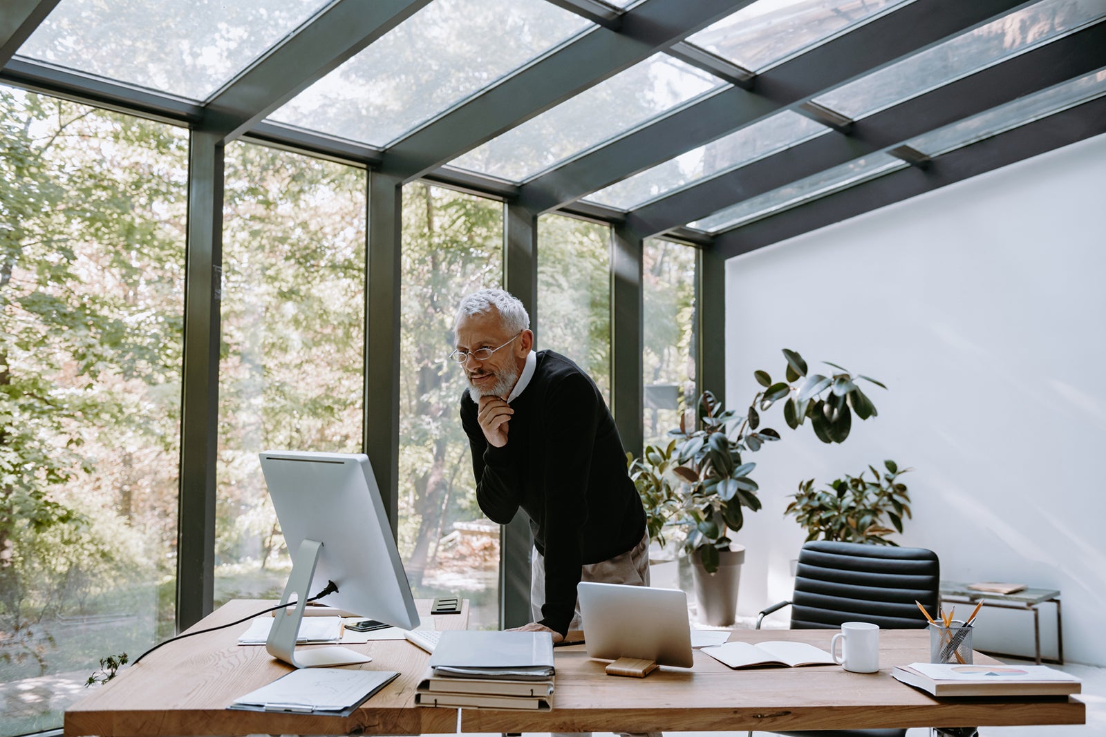 man standing over a desk looking at a computer monitor