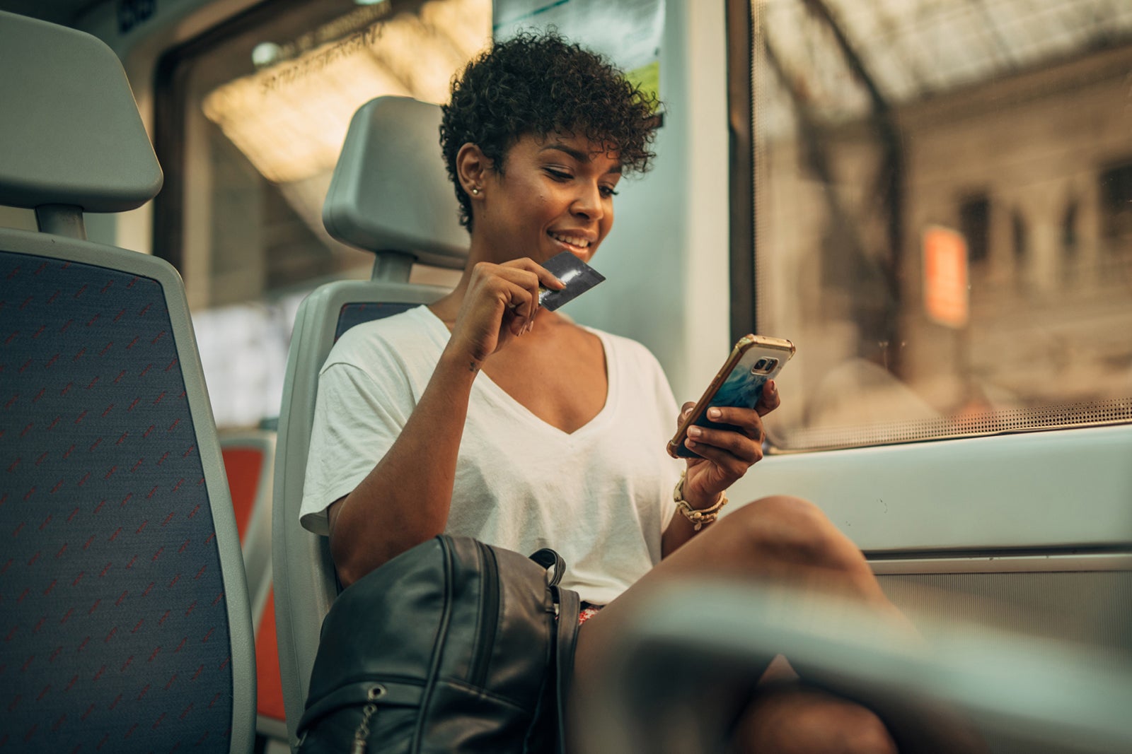 woman holding credit card and using mobile phone