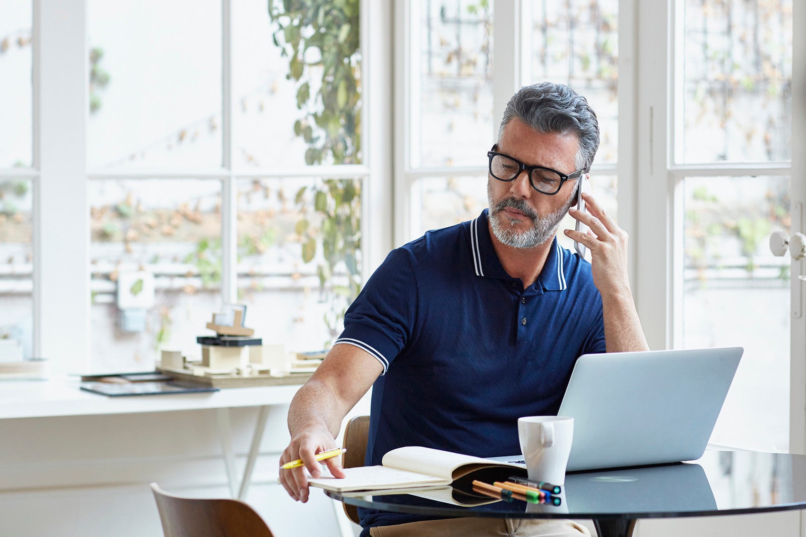 Businessman using mobile phone while writing notes