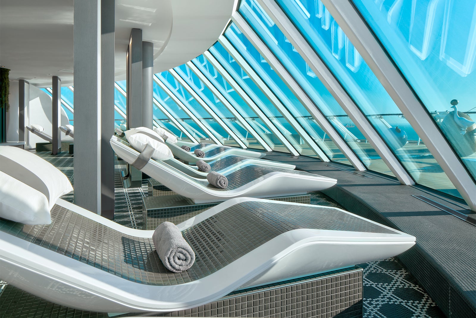 A thermal suite on a cruise ship with tile loungers facing floor-to-ceiling windows