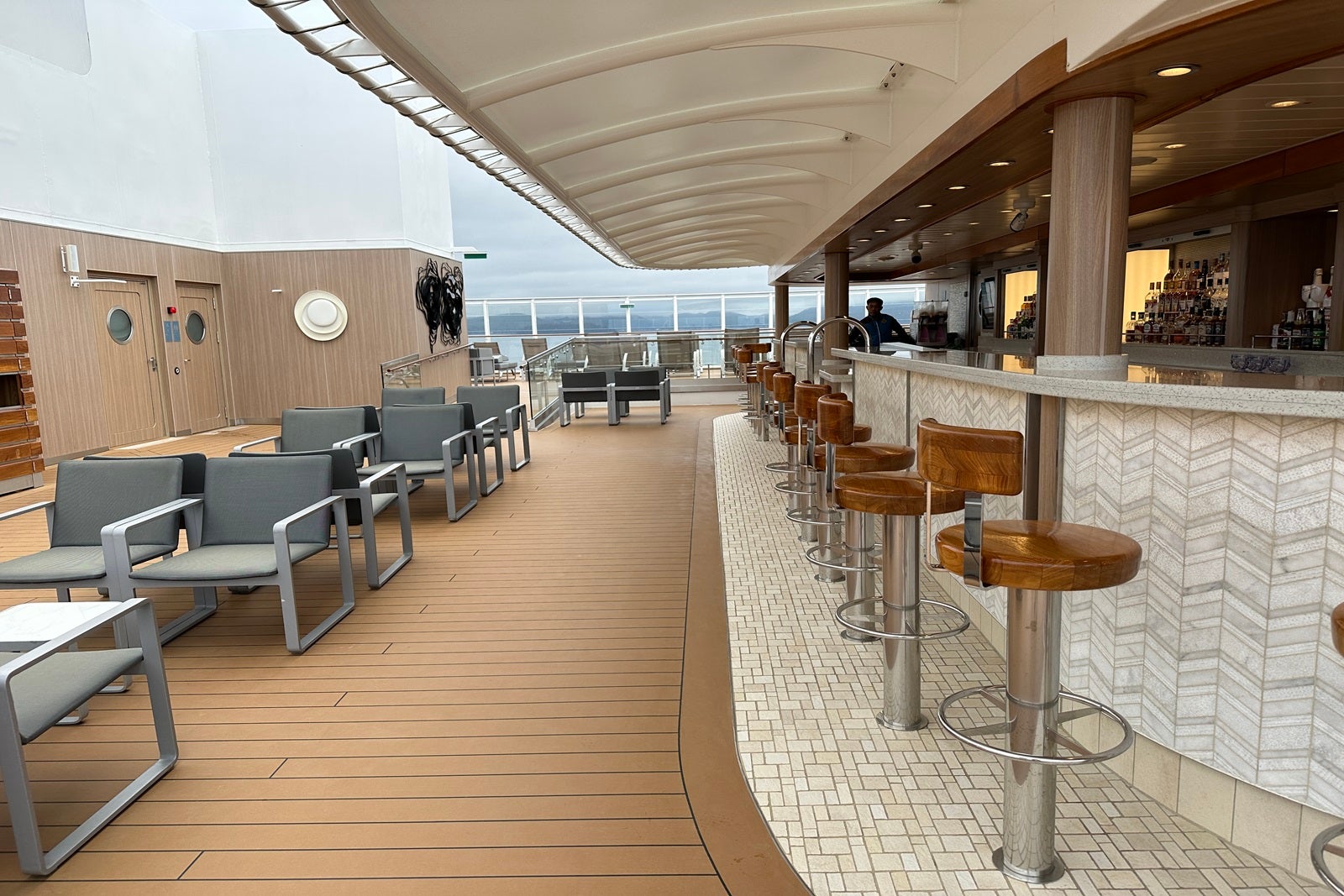 Clusters of tables and chairs next to a bar on a cruise ship sun deck