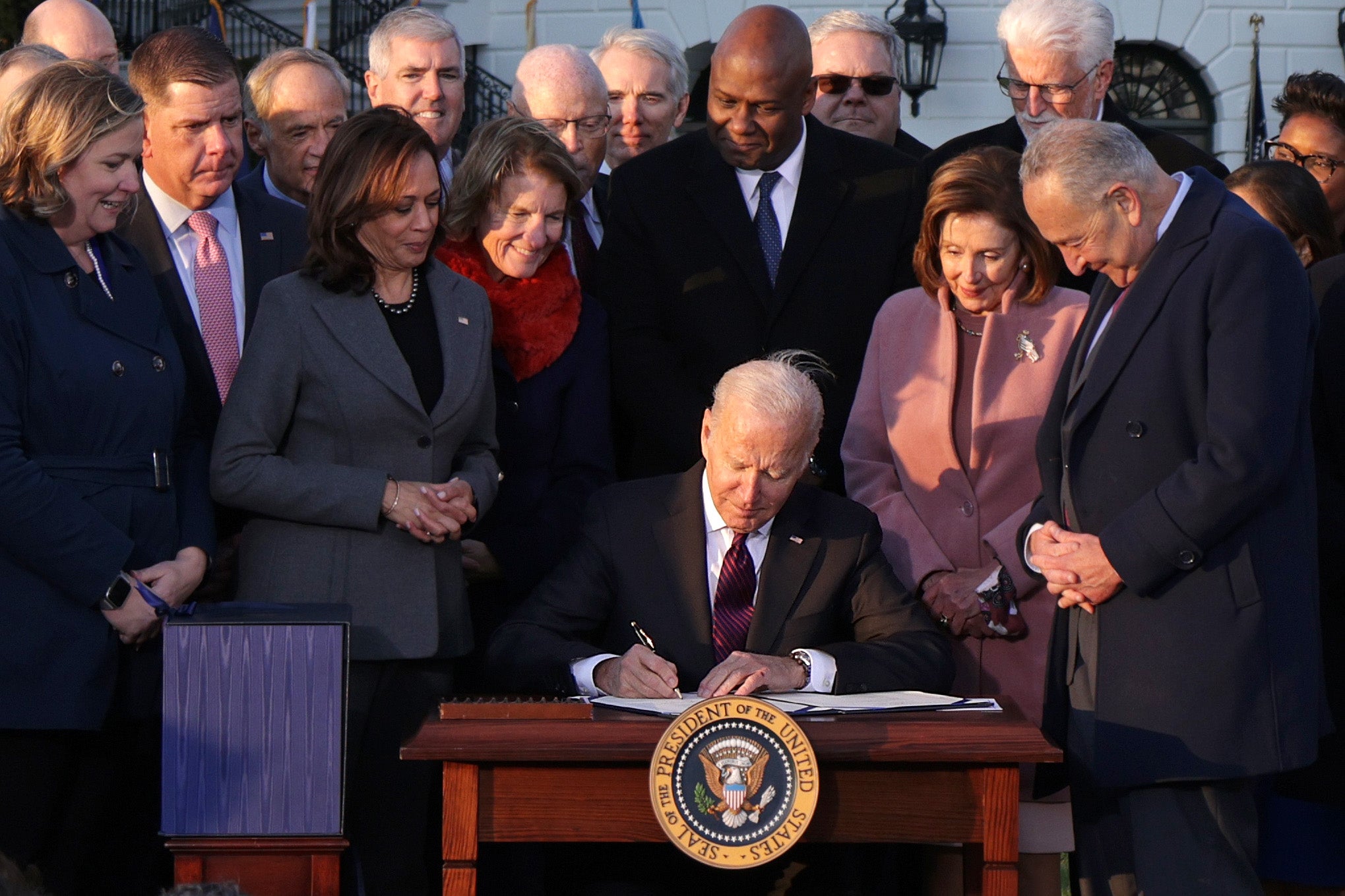  U.S. President Joe Biden signs the Infrastructure Investment and Jobs Act as he is surrounded by lawmakers and members of his Cabinet during a ceremony on the South Lawn at the White House on November 15, 2021 in Washington, DC. The $1.2 trillion package will provide funds for public infrastructure projects including improvements to the country’s transportation networks, increasing rural broadband access, and projects to modernizing water and energy systems. (Photo by Alex Wong/Getty Images)