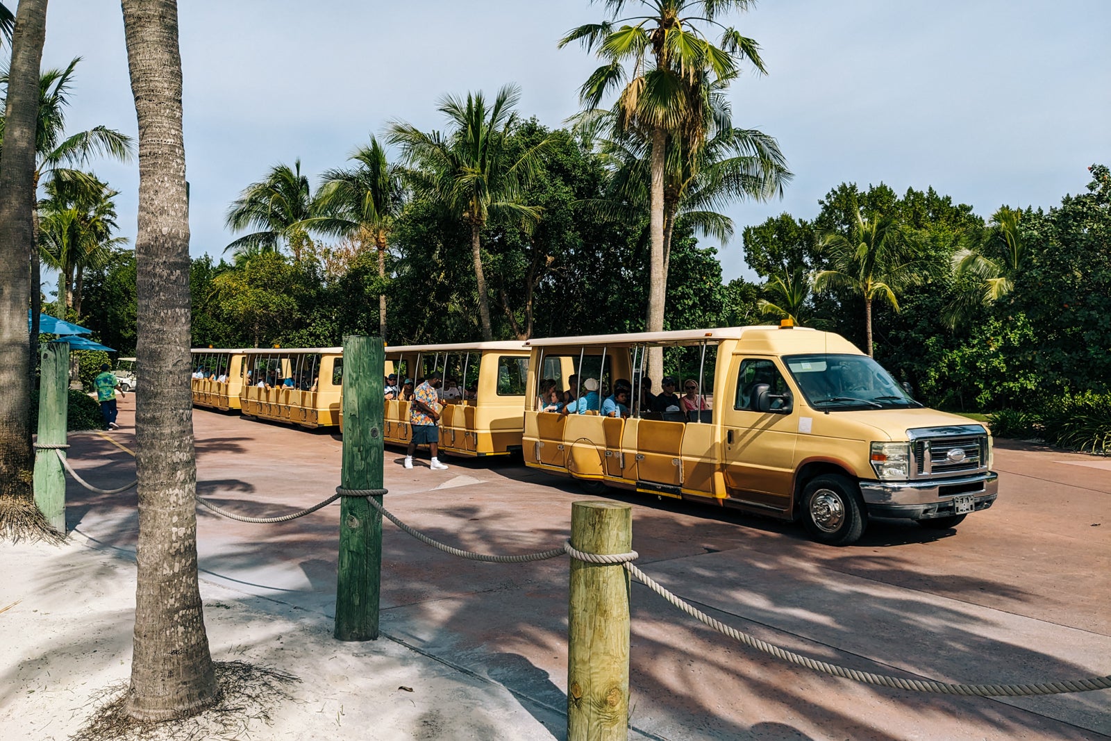 Tram driving palm-tree lined row on Disney Cruise Line private island.