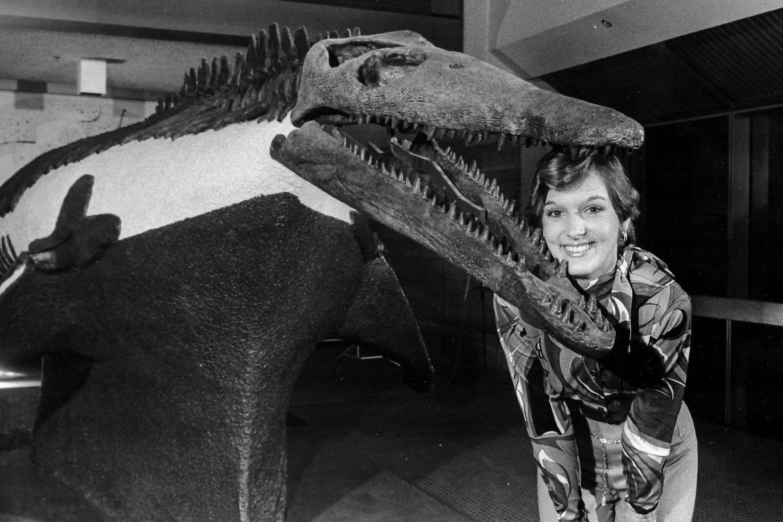 Braniff Flight Attendant poses with a Plesiosaur fossil found during DFW excavation