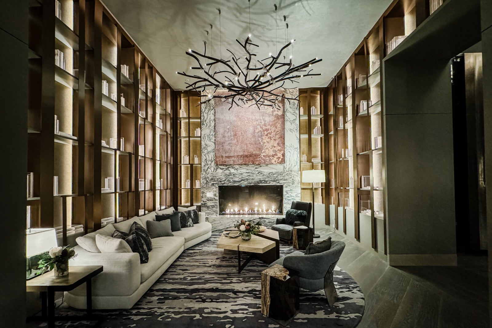 a hotel lobby decorated with neutral colors and a sofa, chairs and fireplace