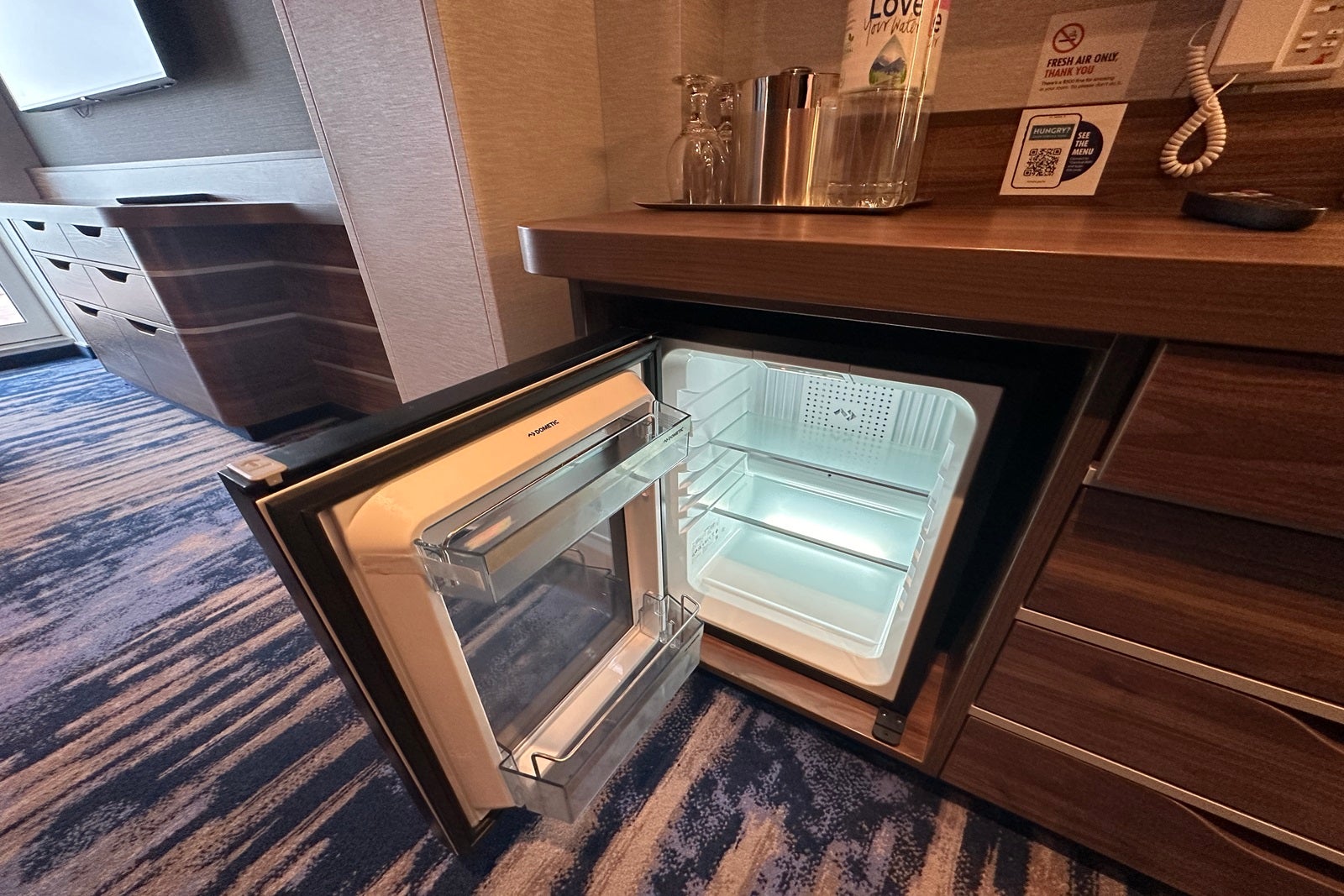 A mini-fridge sits open in a cruise ship cabin