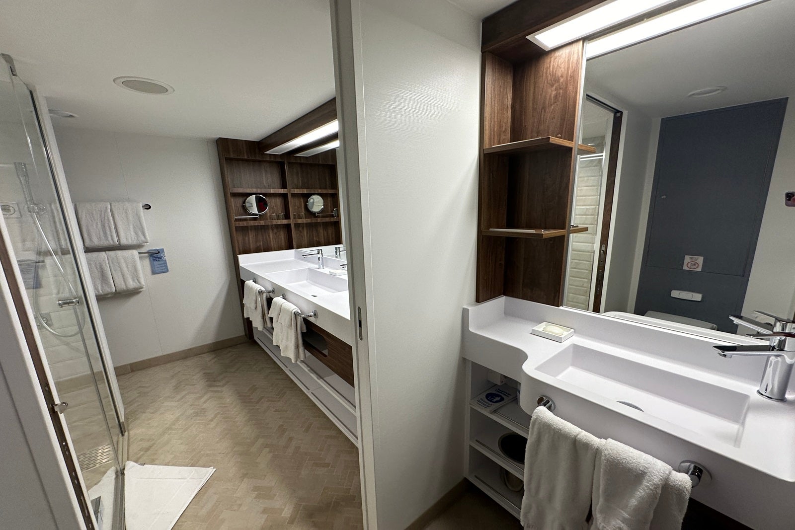 A large cruise ship bathroom, split into an area for showering and a toilet area with sinks