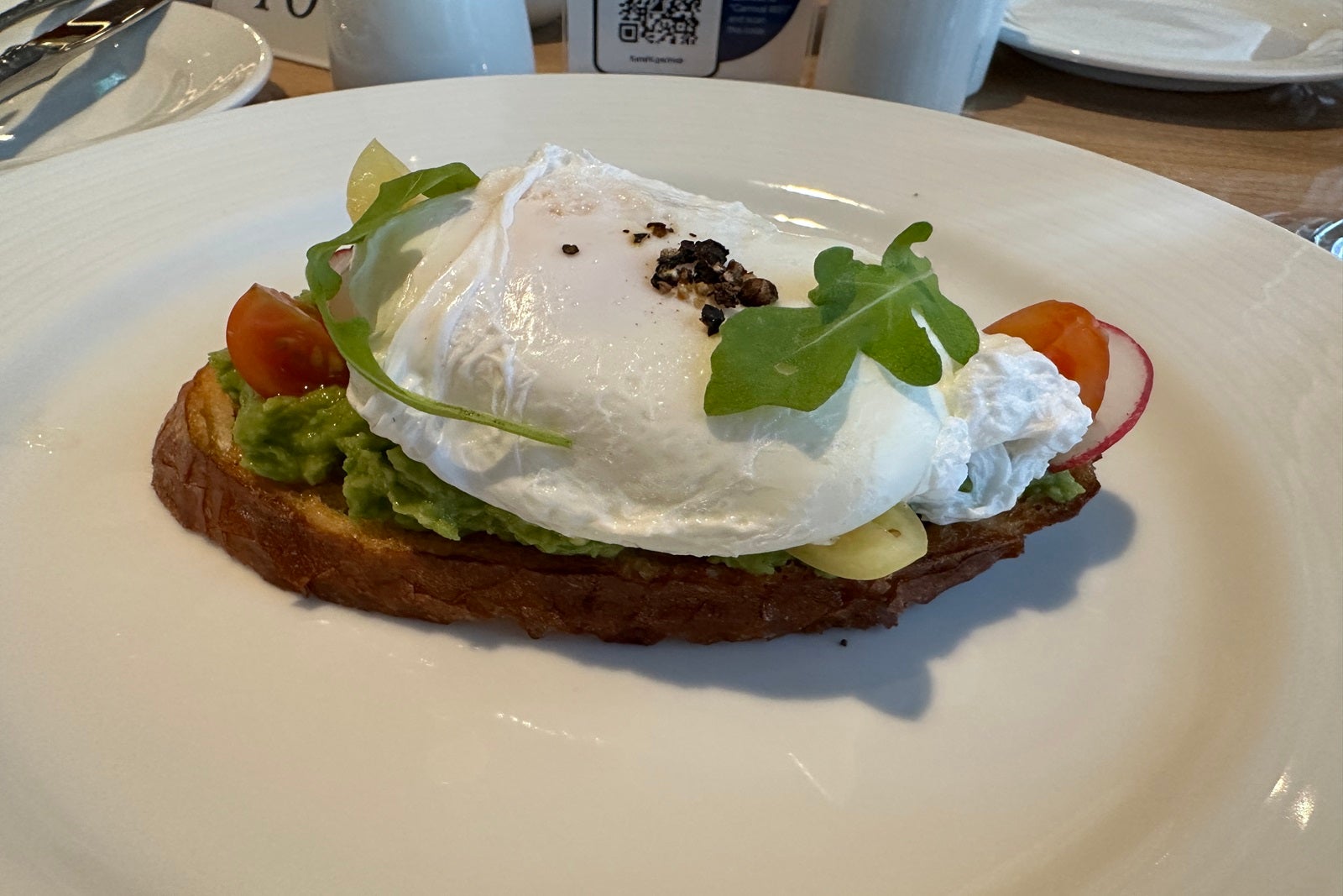 Avocado toast topped with a poached egg on a white plate