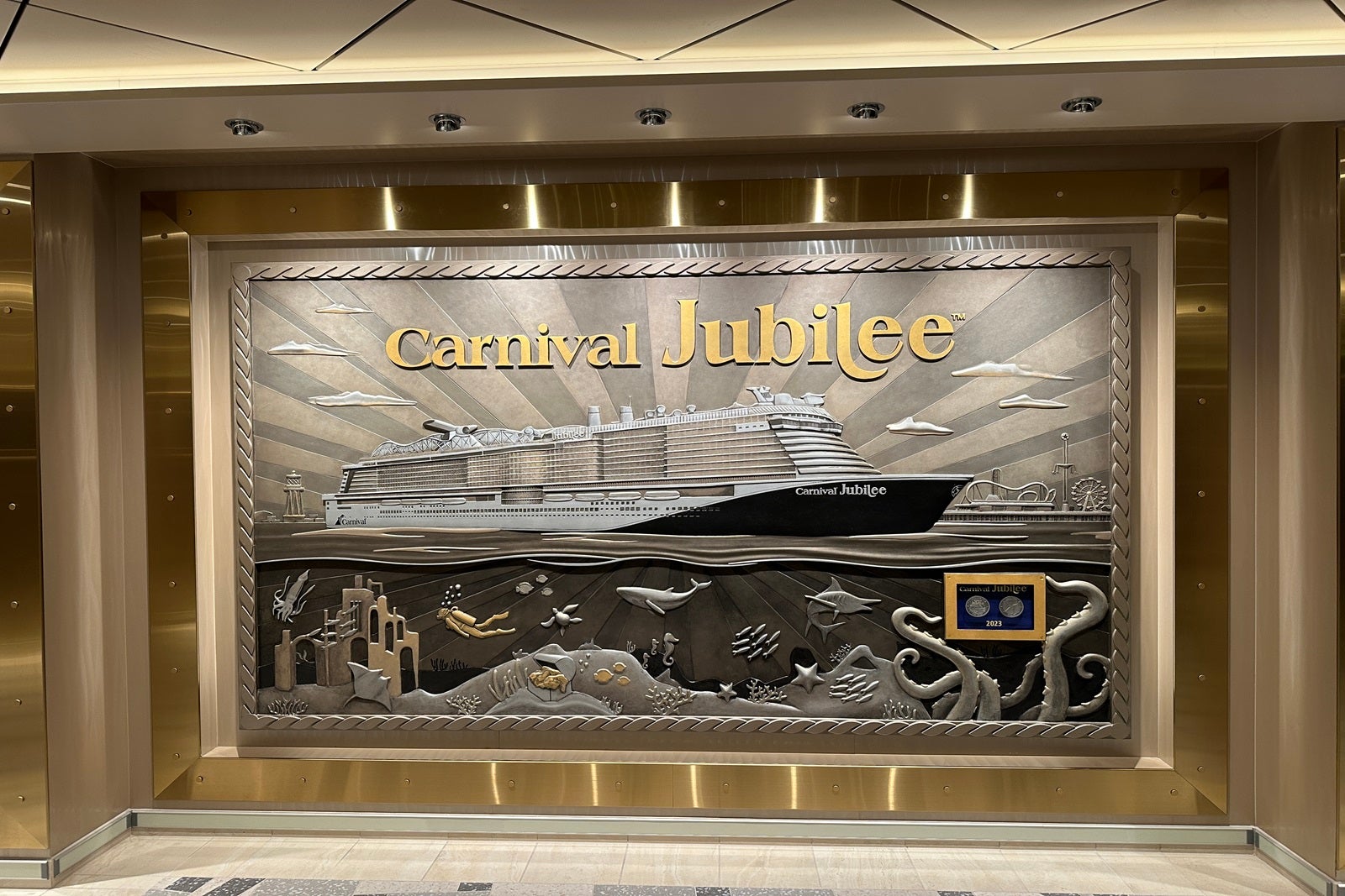 A metal wall sculpture depicts the Carnival Jubilee cruise ship