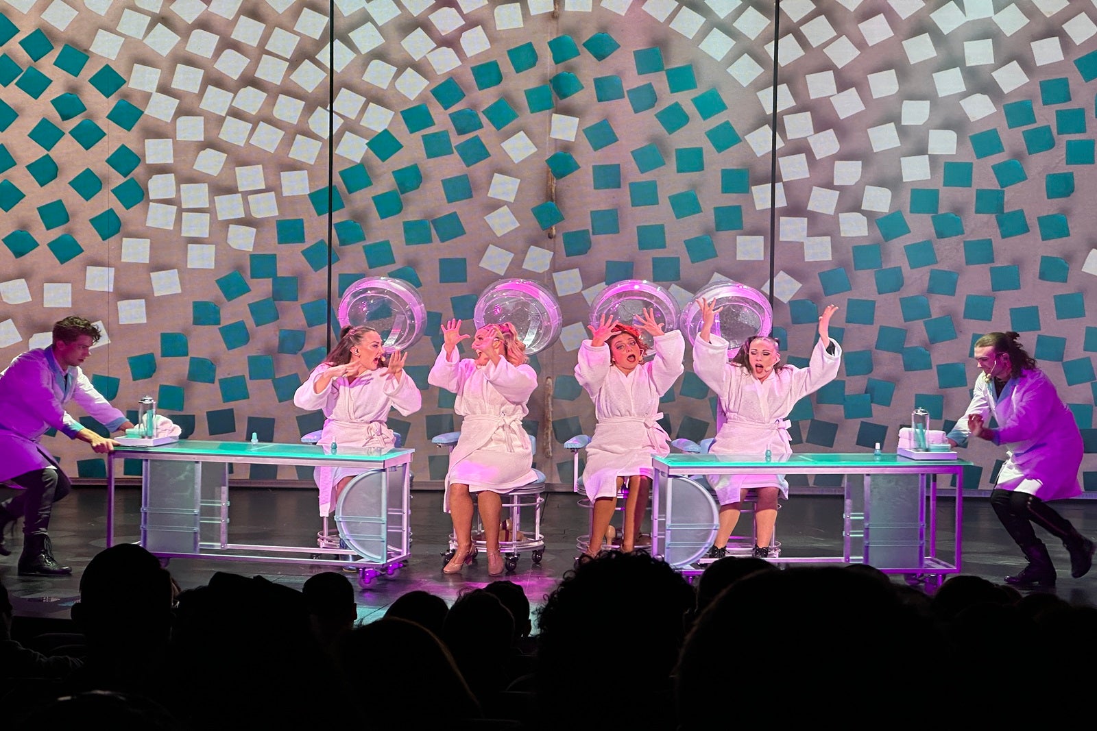 Four performers on a stage get their hair done as part of a show