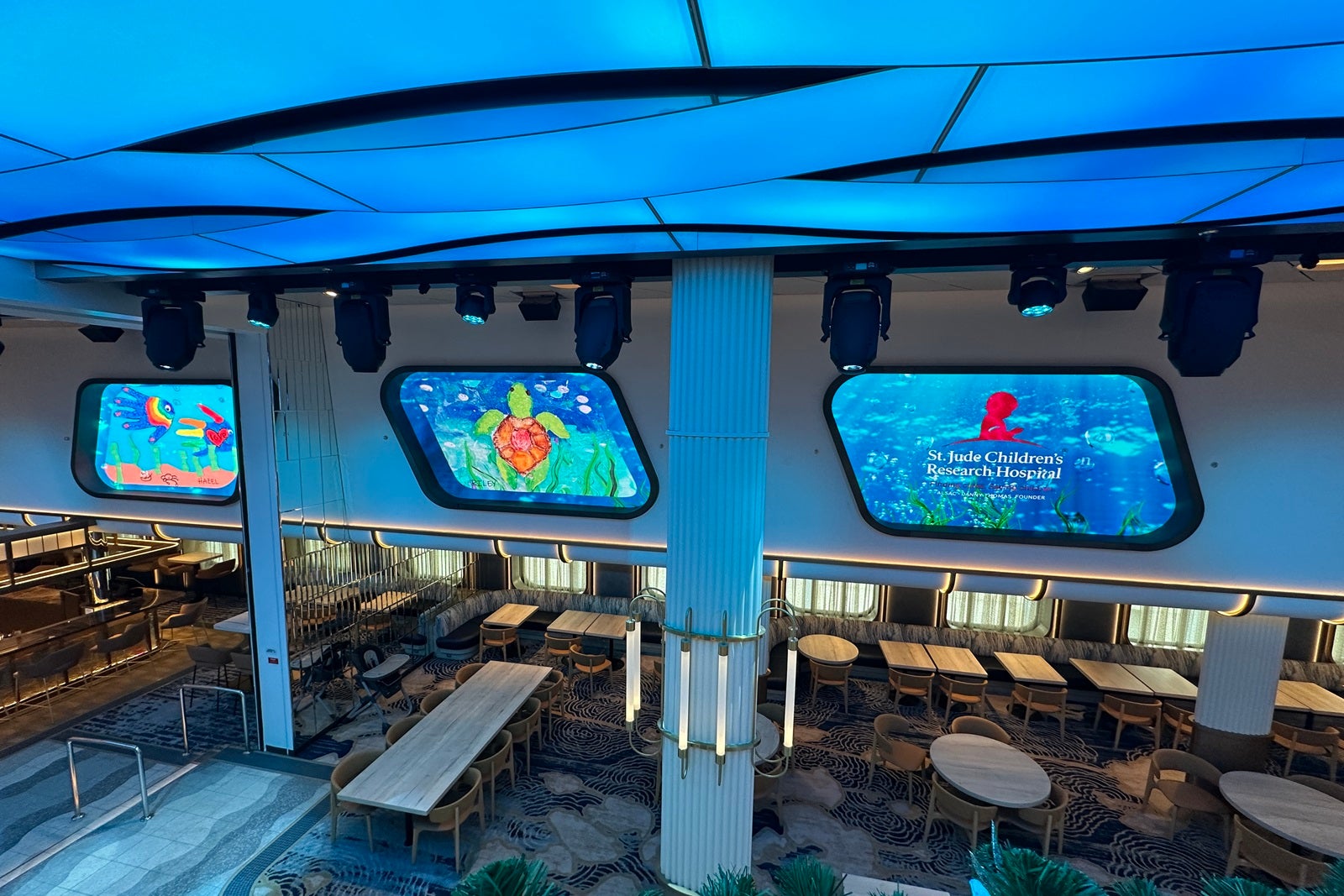 Two LED screens shaped like cruise ship windows show nautically themed children's drawings.