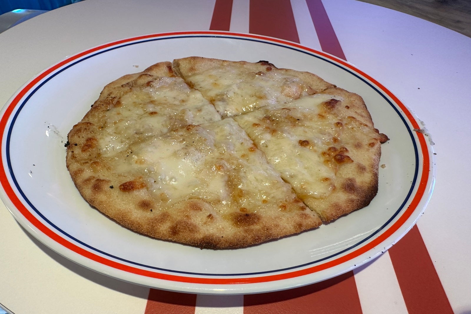 A small cheese pizza on a white plate
