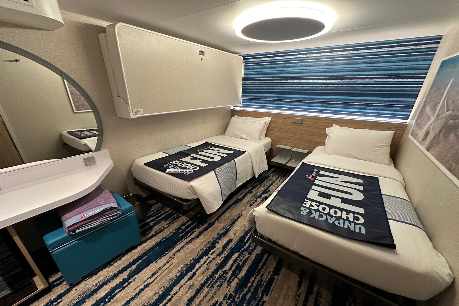An interior cruise cabin with two twin beds and a pull-down bunk, plus a vanity