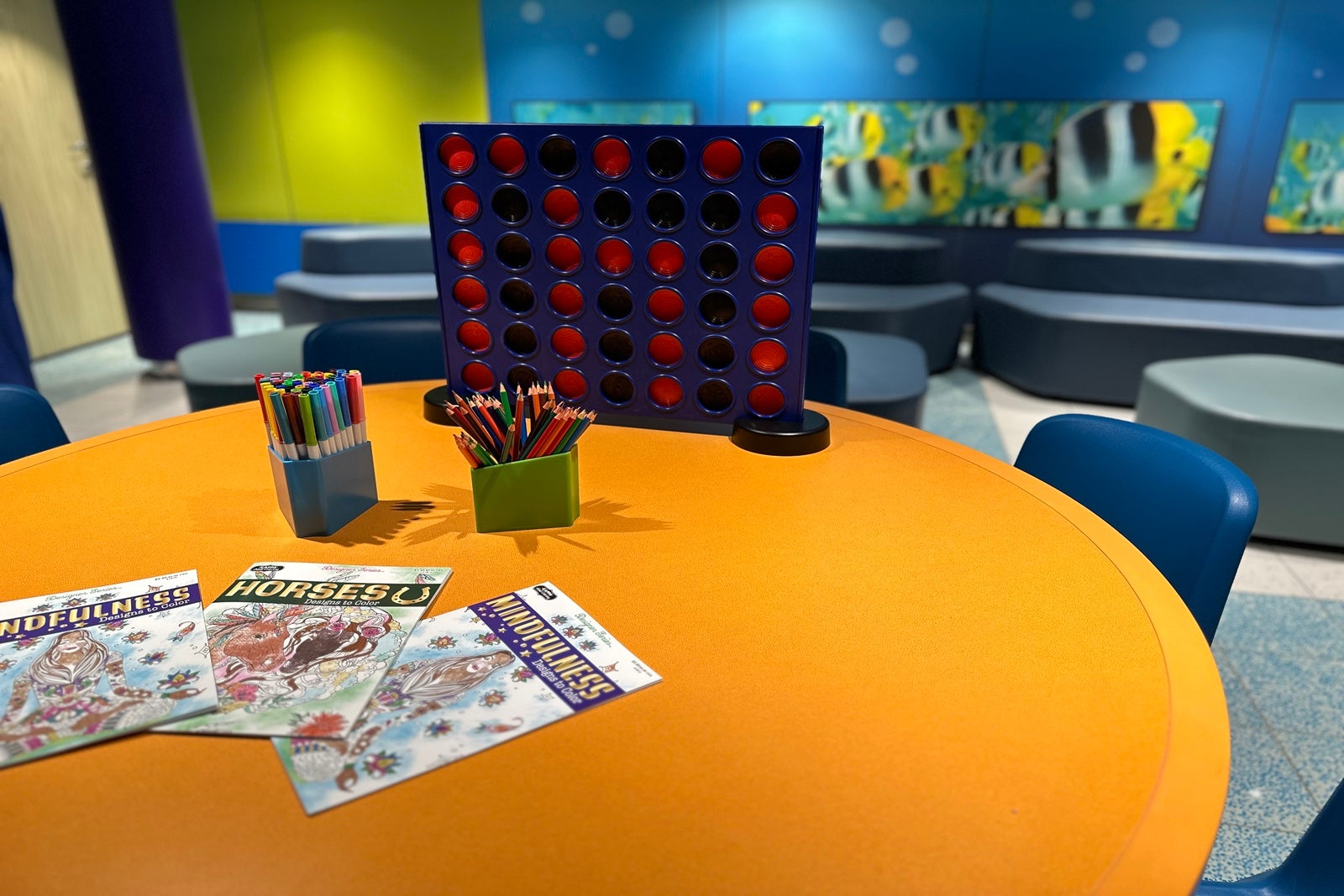 A yellow table set up with coloring supplies and games