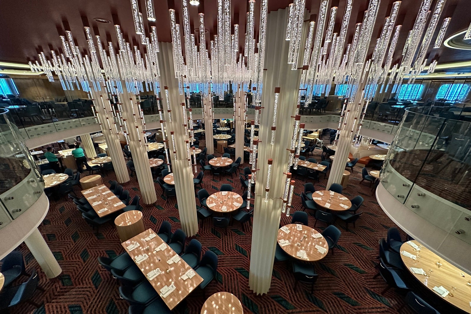 An aerial view of a cruise ship main dining room with tables and chairs and Hogwarts-style lighting resembling candlesticks