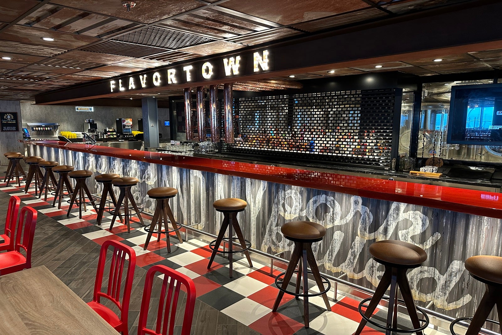 A metallic, industrial-looking bar with a red countertop, stools and a sign that reads "Flavortown"