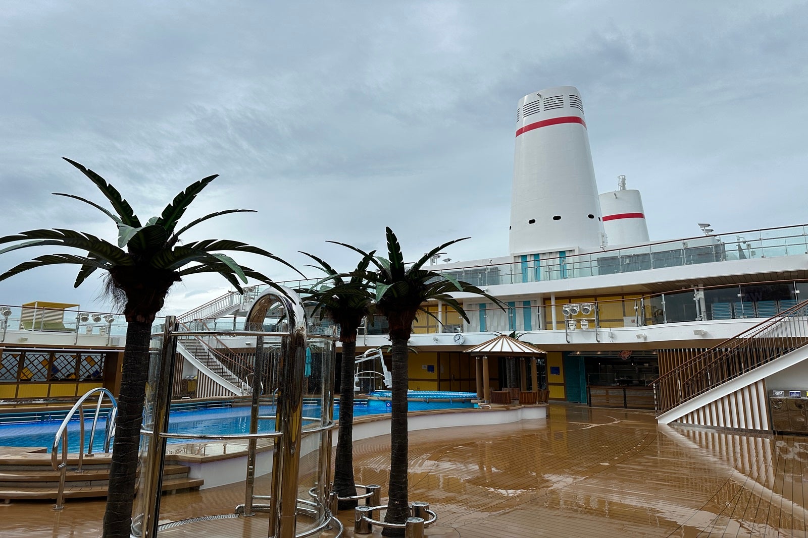 The pool area on a cruise ship with faux palm trees and vintage smokestacks