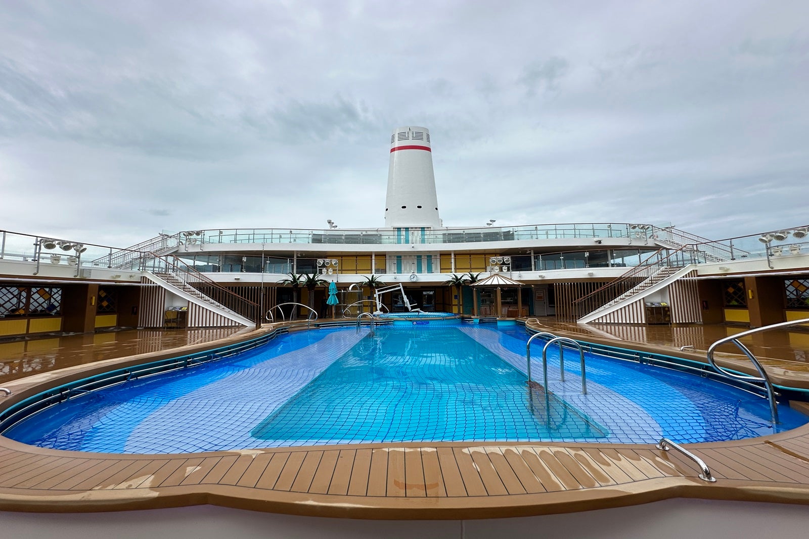 A cruise ship pool with smokestacks in the background