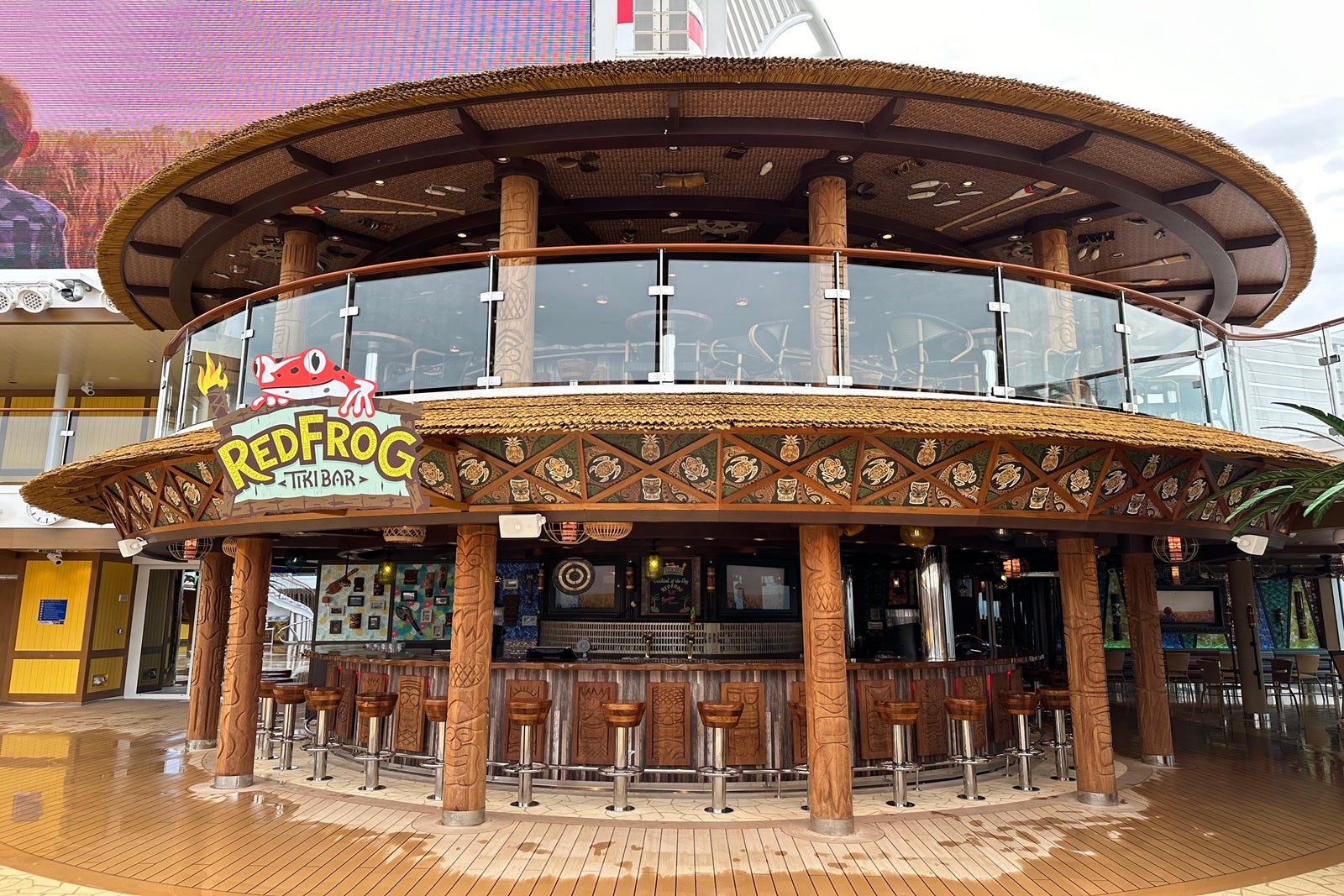 A round, two-deck tiki bar on the pool deck of a cruise ship