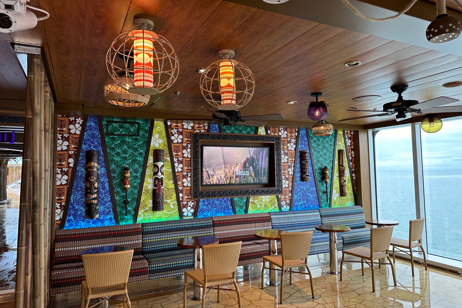 The inside of a tiki bar with rustic seating, tribal light fixtures and colorful wall art