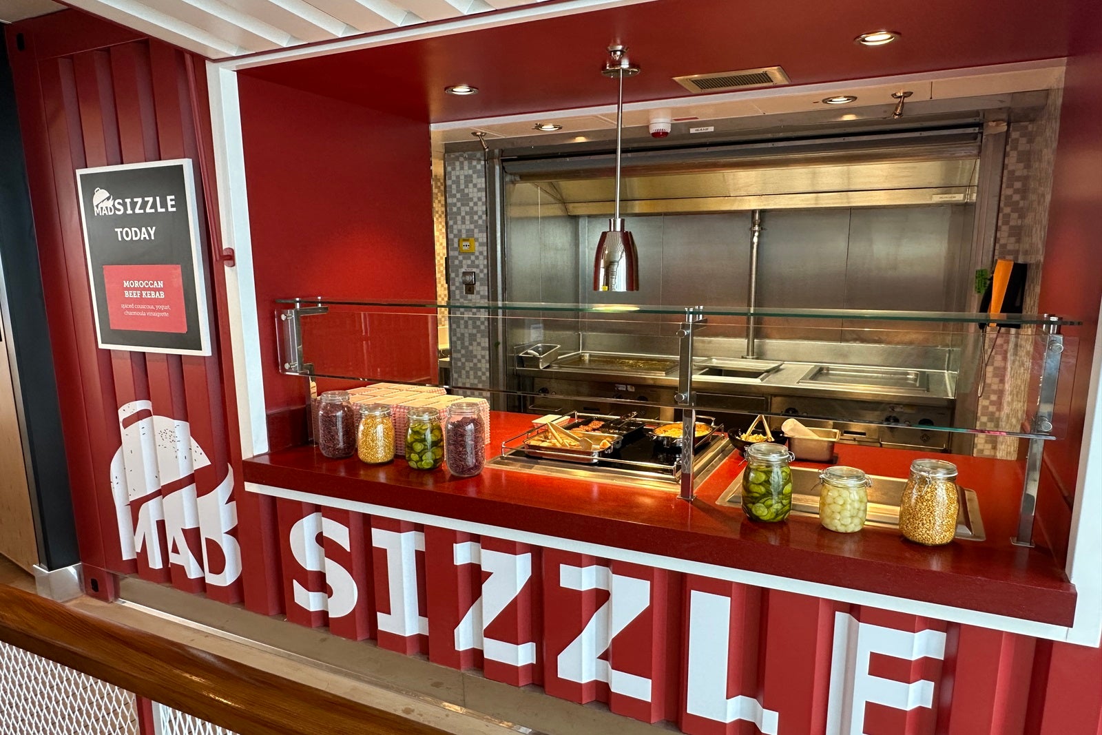 A red walk-up counter-service food window with the words "Mad Sizzle" printed on it in white