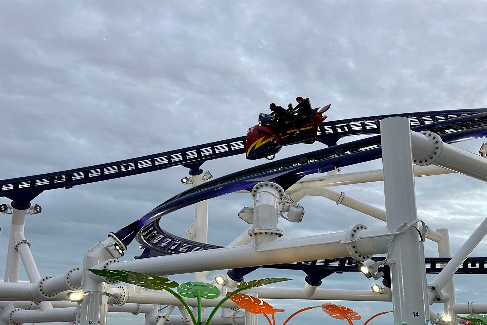 Two passengers ride a roller coaster around the top deck of a cruise ship