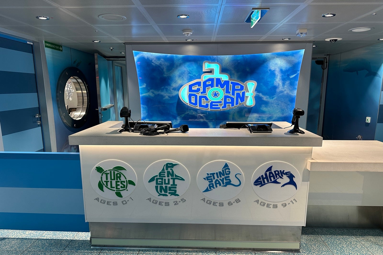A reception desk with an LED screen behind it that reads "Camp Ocean"