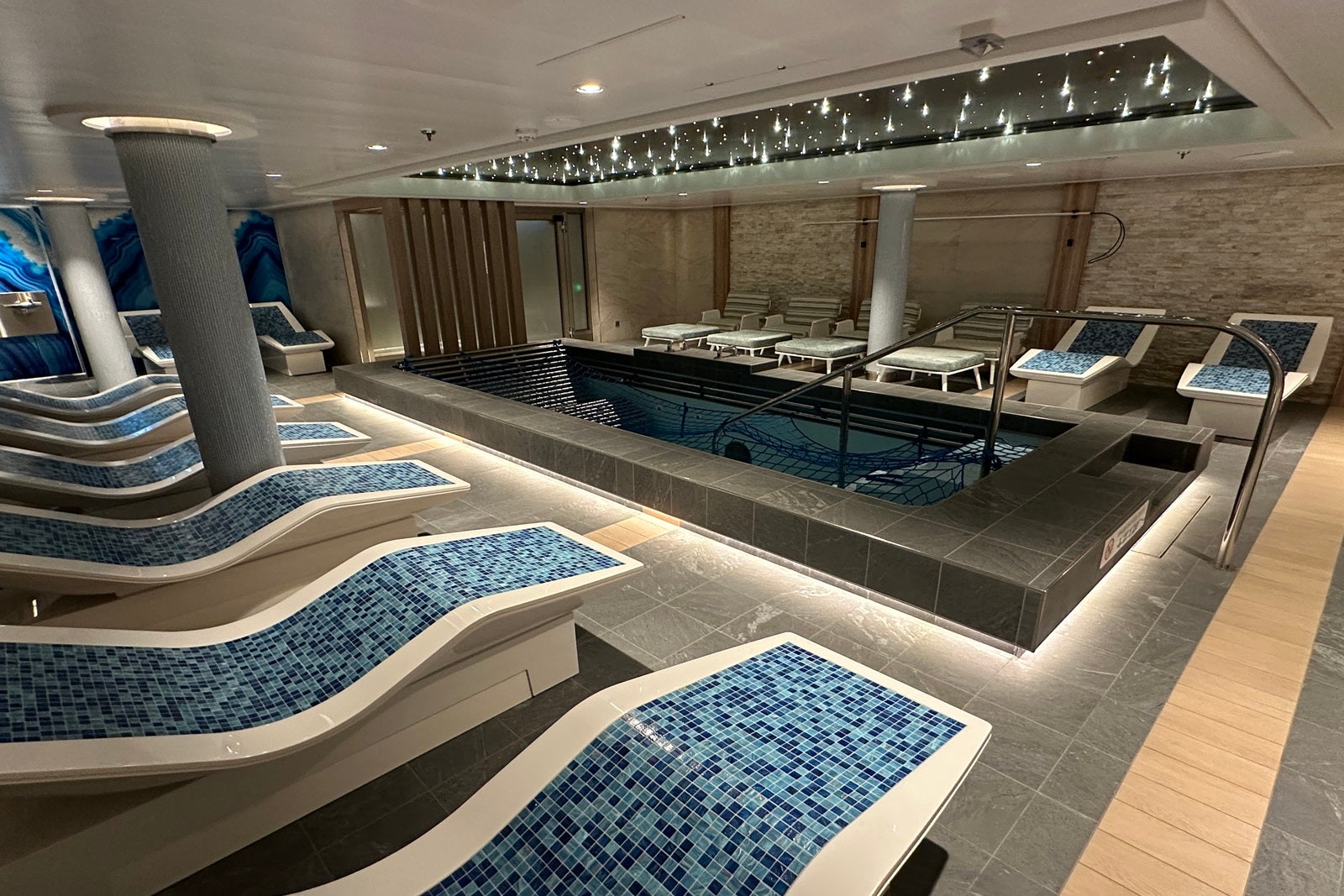 A spa thermal suite with rows of tile loungers and a central whirlpool