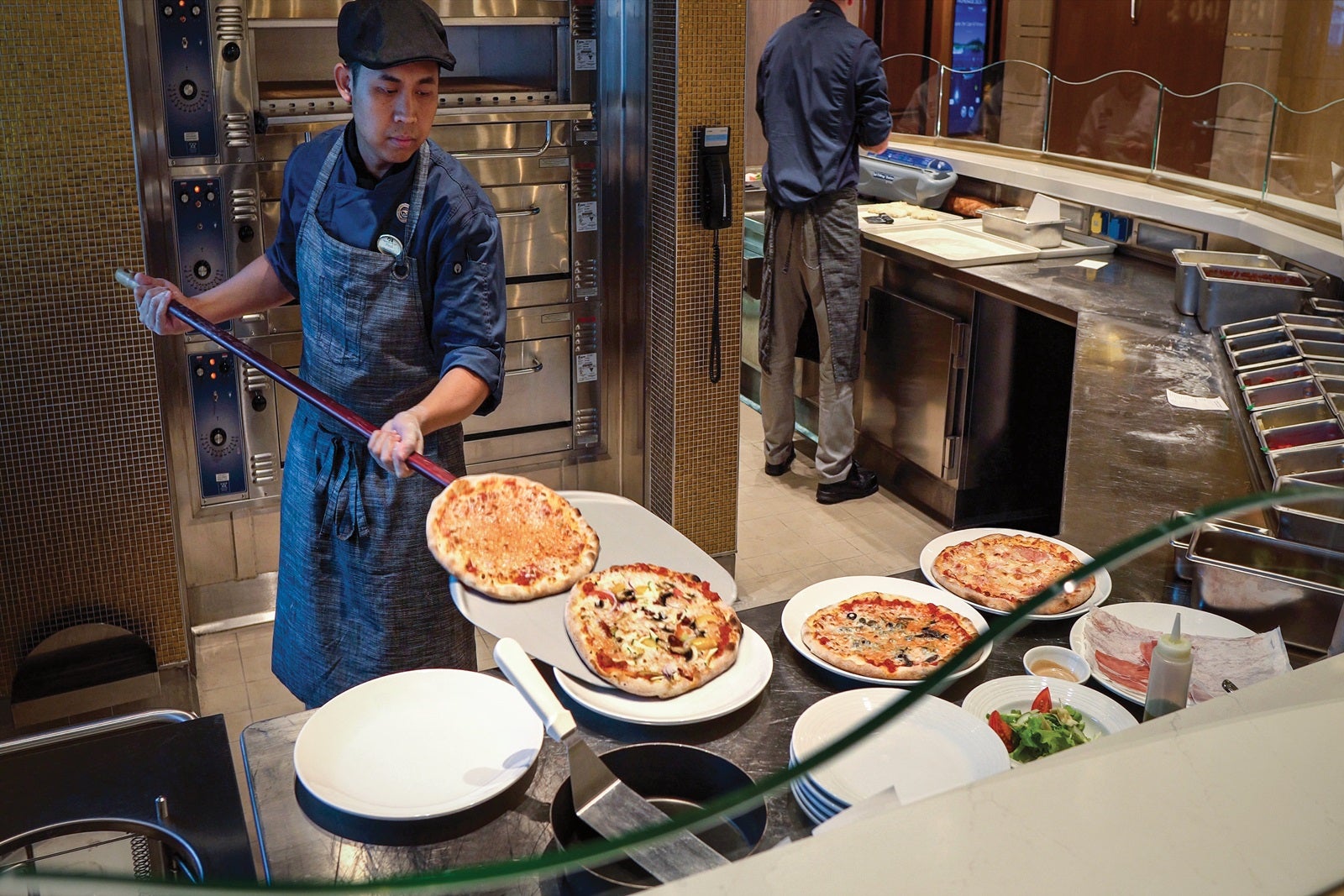 A crew member plates pizzas at Alfredo's on Sky Princess