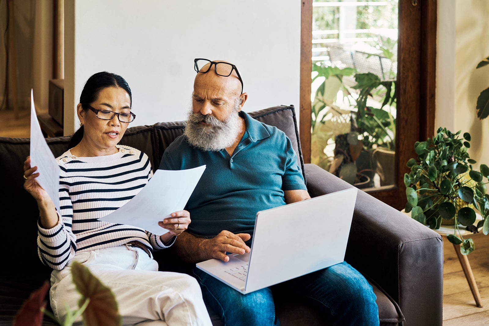 A couple sitting on a sofa reviewing some documents 