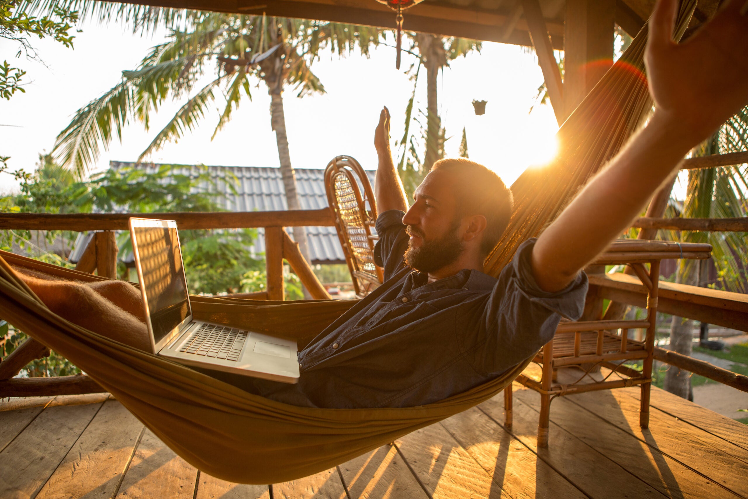 Successful businessman on hammock with computer-Sunset