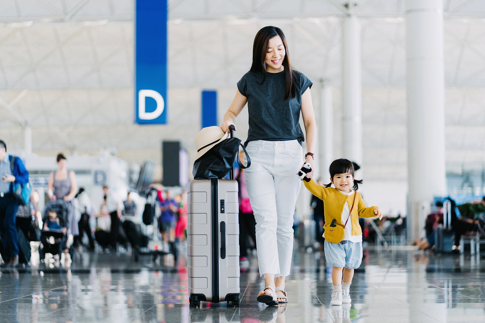 Joyful young Asian mother holding hands of her cute little daughter, walking through airport concourse and travelling by plane on a vacation. Family travel and vacation. Embark on a new journey with the family