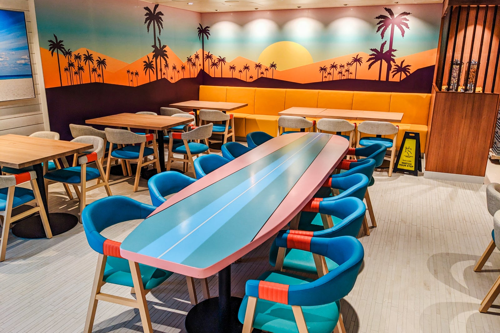 Table that looks like surfboard by mural of palm trees