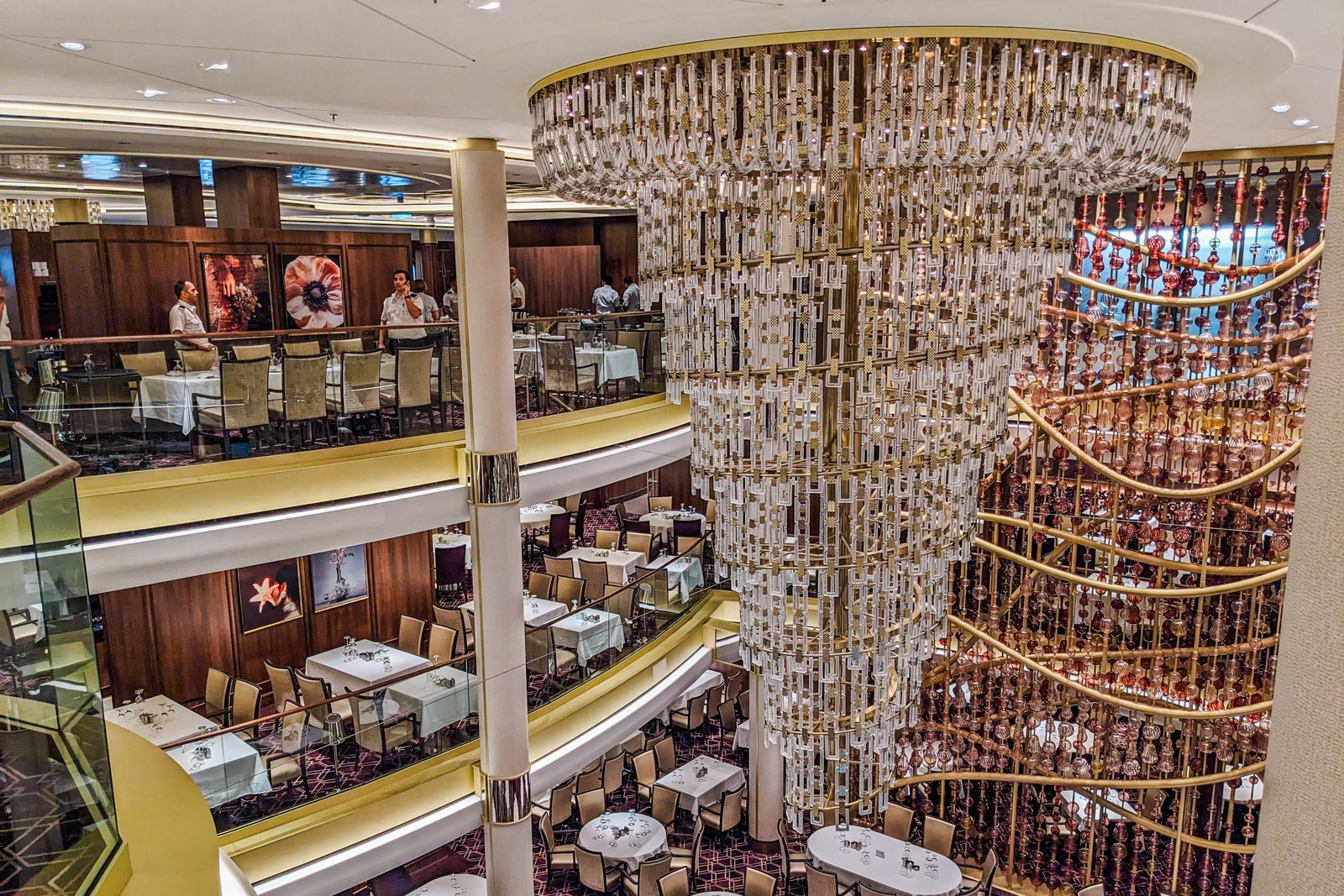 Giant multi-tiered glass chandelier above three-deck-high cruise ship dining room