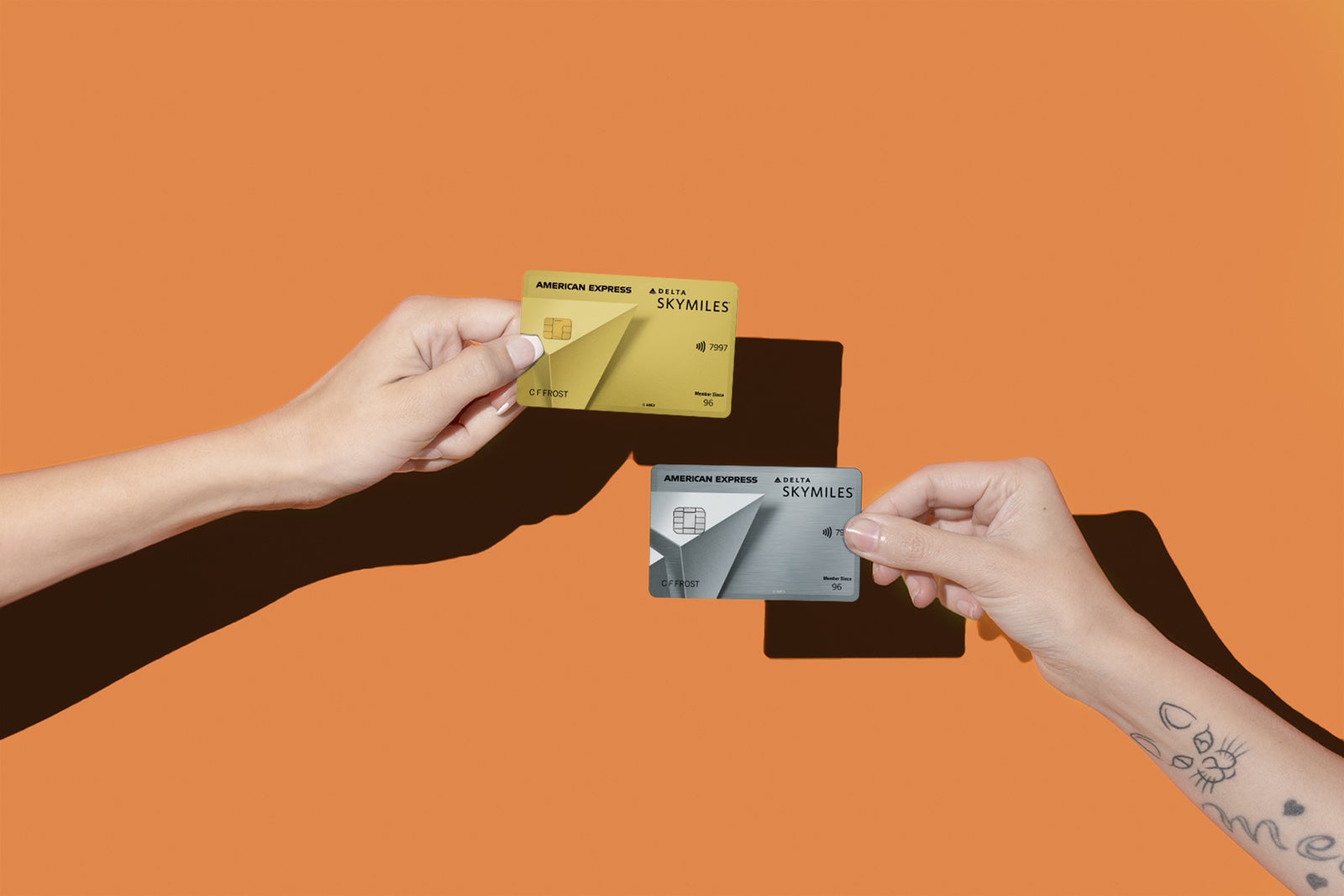 Two hands holding up two American Express Delta Skymiles Cards