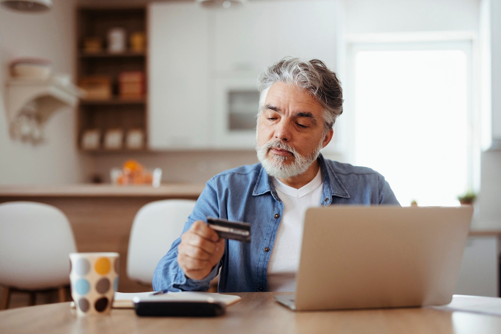 Man using a laptop and holding a credit card