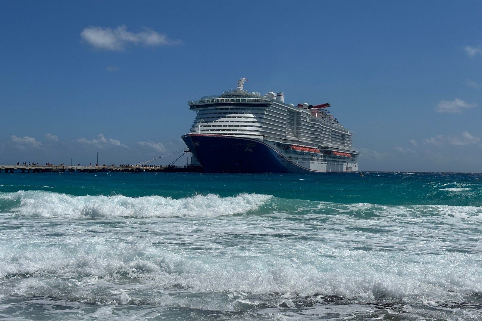 A cruise ship docked in Costa Maya with teal waves crashing in front of it