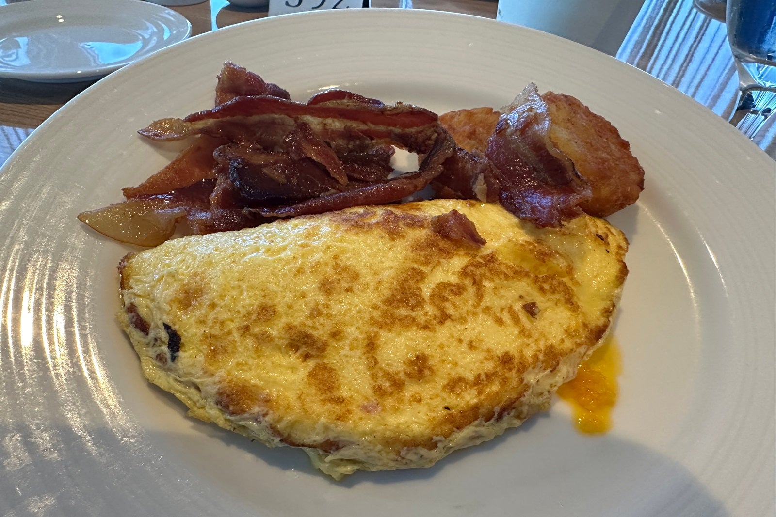 An omelet and bacon on a white plate
