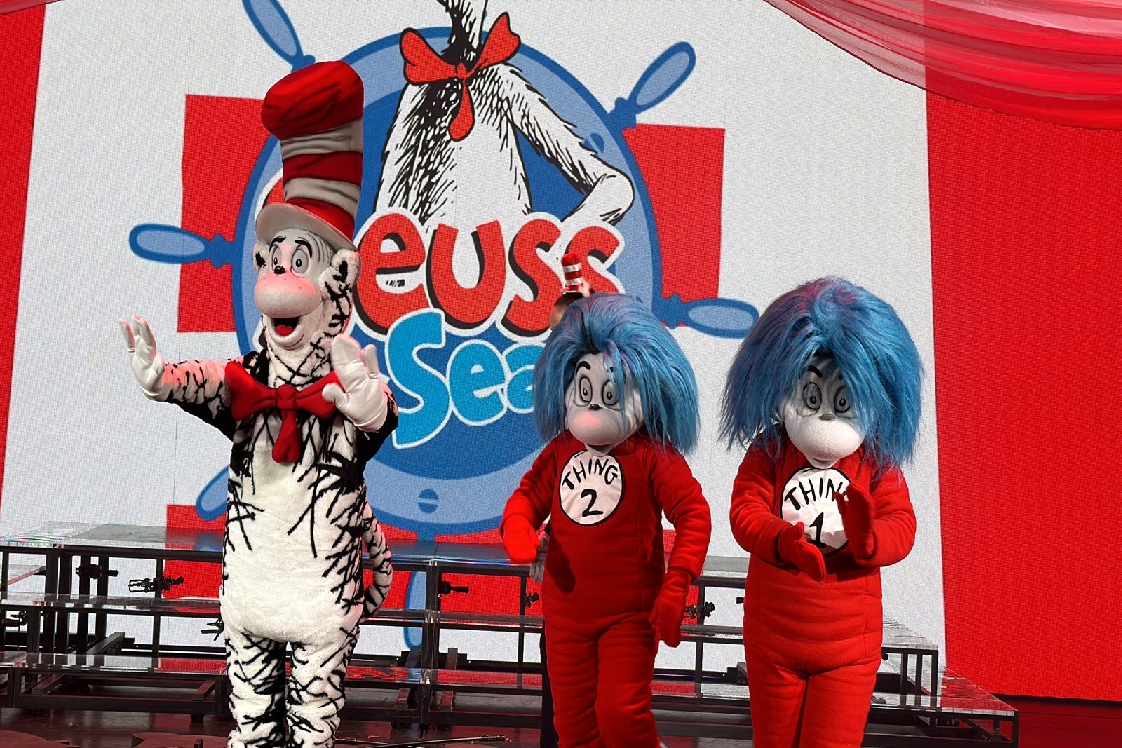 The Cat in the Hat and Things 1 and 2 standing on a stage in front of a Dr. Seuss backdrop