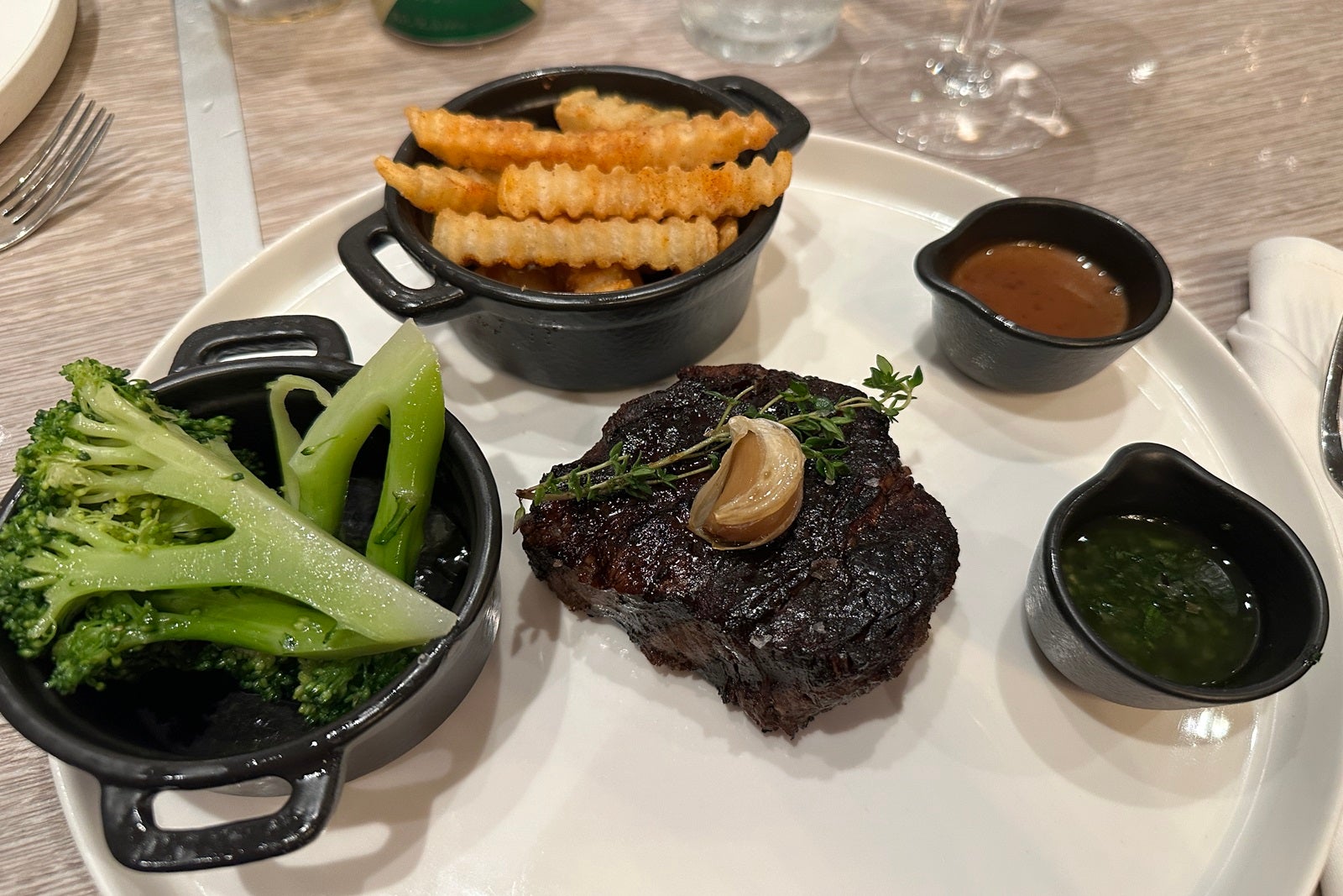 A white plate with broccoli, steak and fries