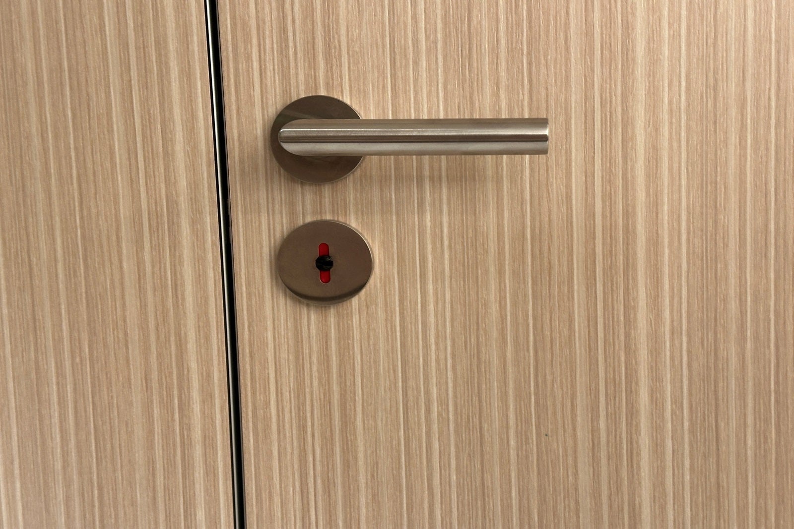 A bathroom stall door handle showing red for occupied
