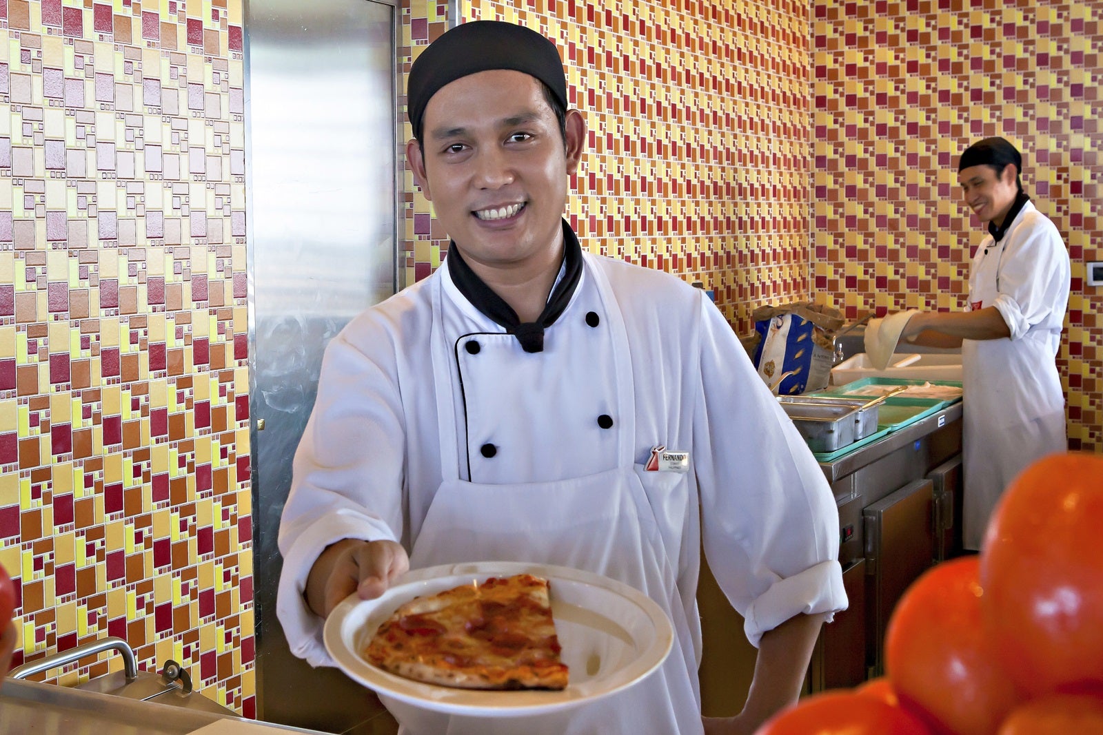 A cruise ship crew member offers a plate of pizza