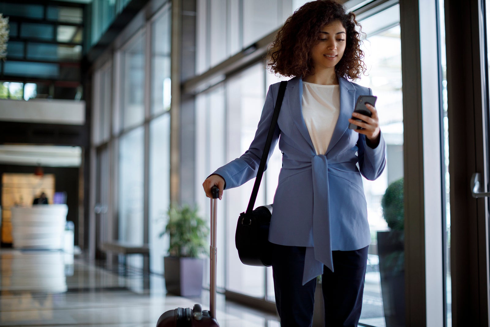 business woman with luggage on phone in hotel lobby