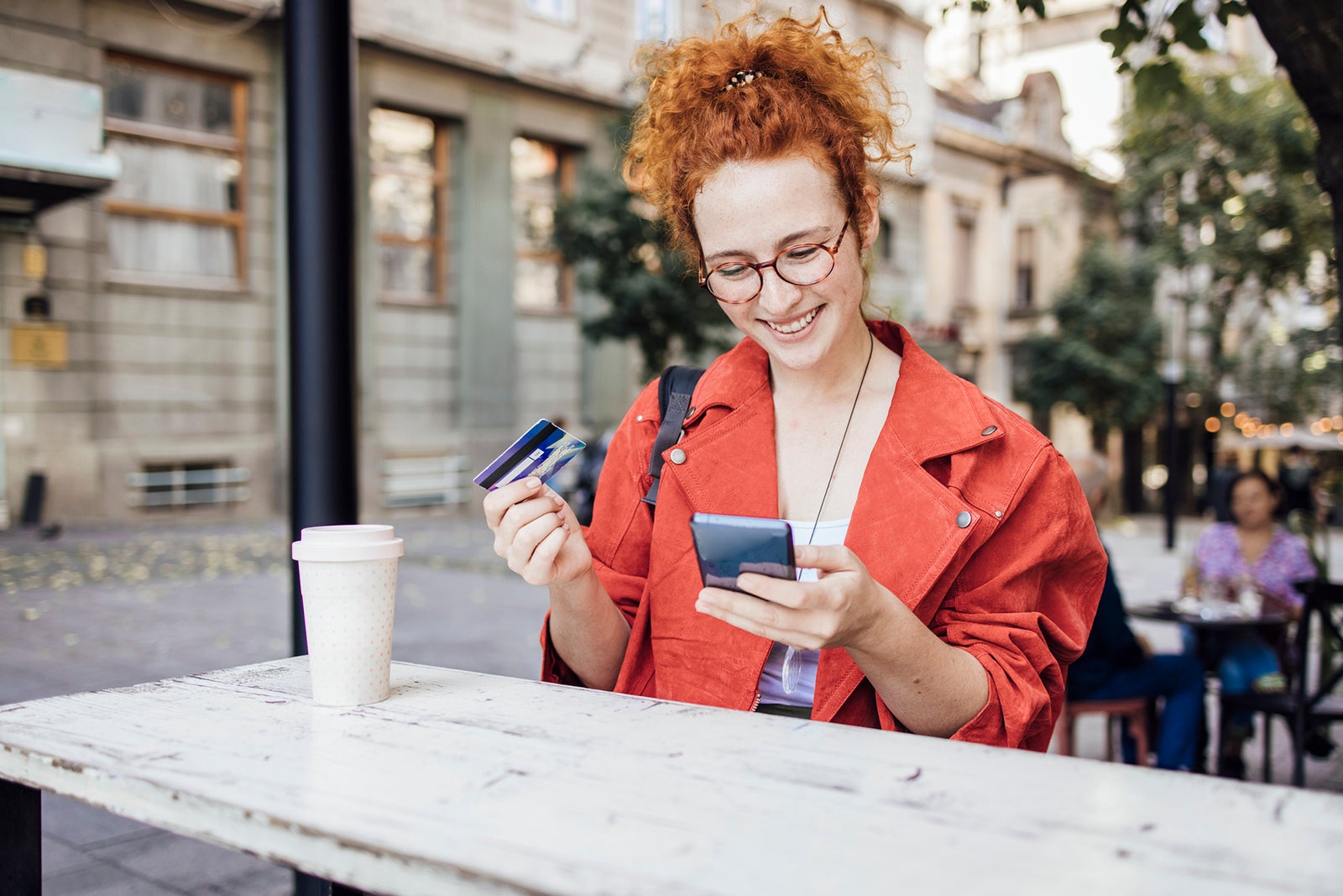 Woman sitting outside holding two credit cards