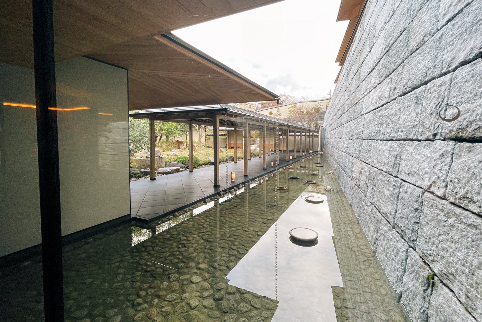 Indoor/outdoor hallway flanked by pond lined with river stones at Park Hyatt Kyoto