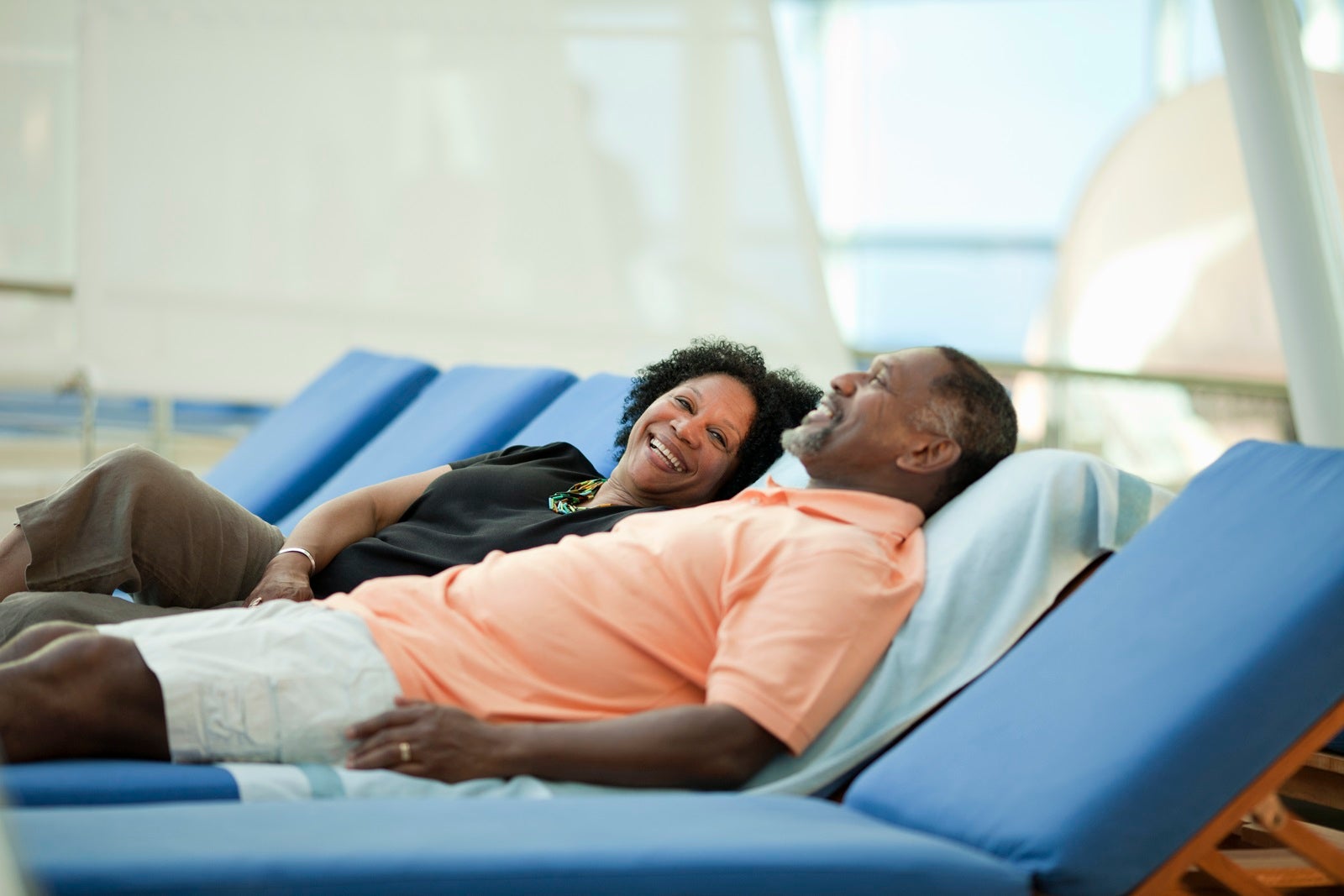A happy couple lying on deck chairs on a cruise ship in casual clothing