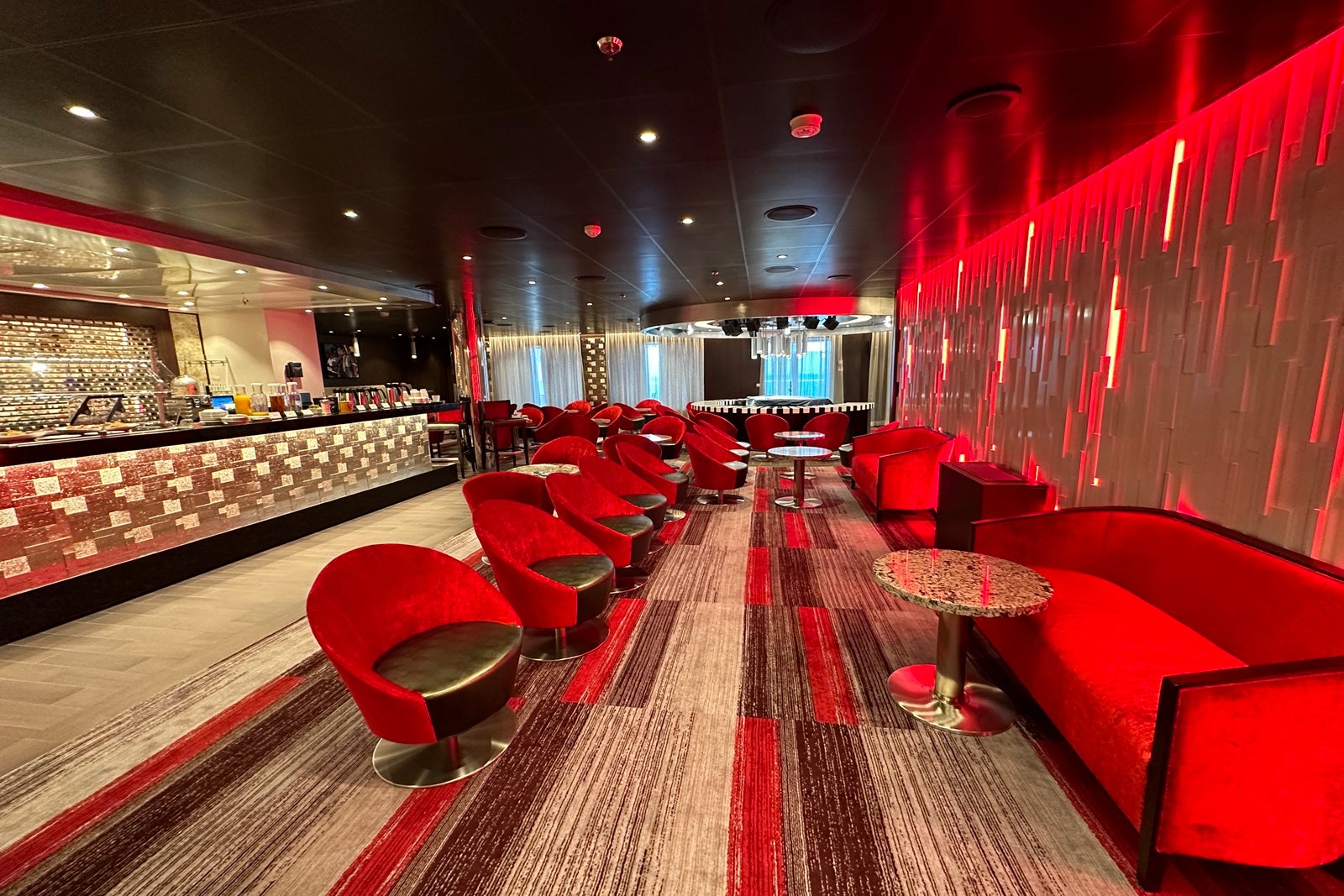 An empty lounge with bright red chairs on a cruise ship