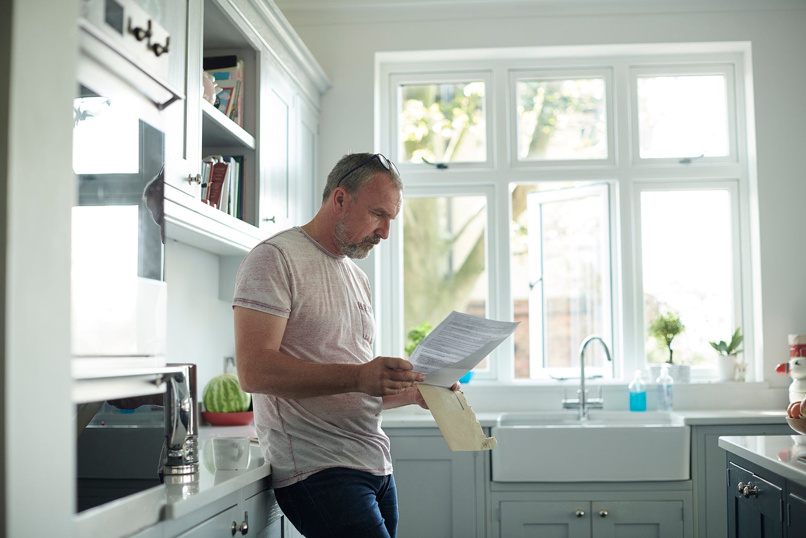 A man reading a bill in his kitchen