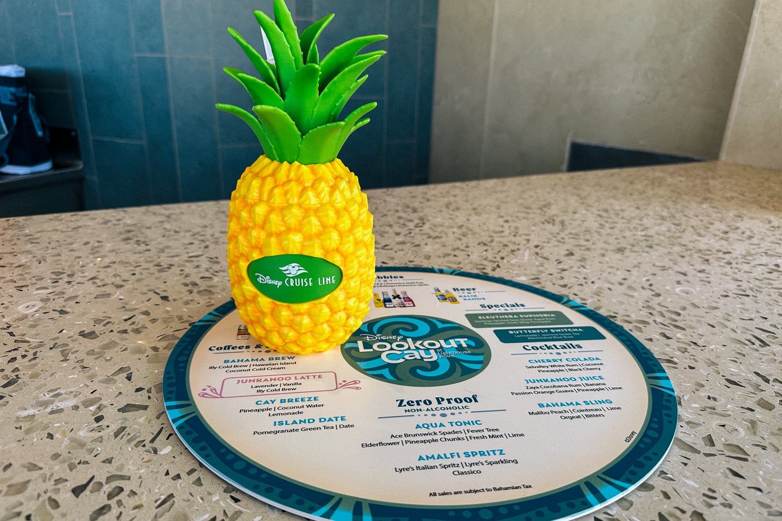 A menu and souvenir pineapple cup from the Reef and Wreck Bar on Disney's Lookout Cay at Lighthouse Point