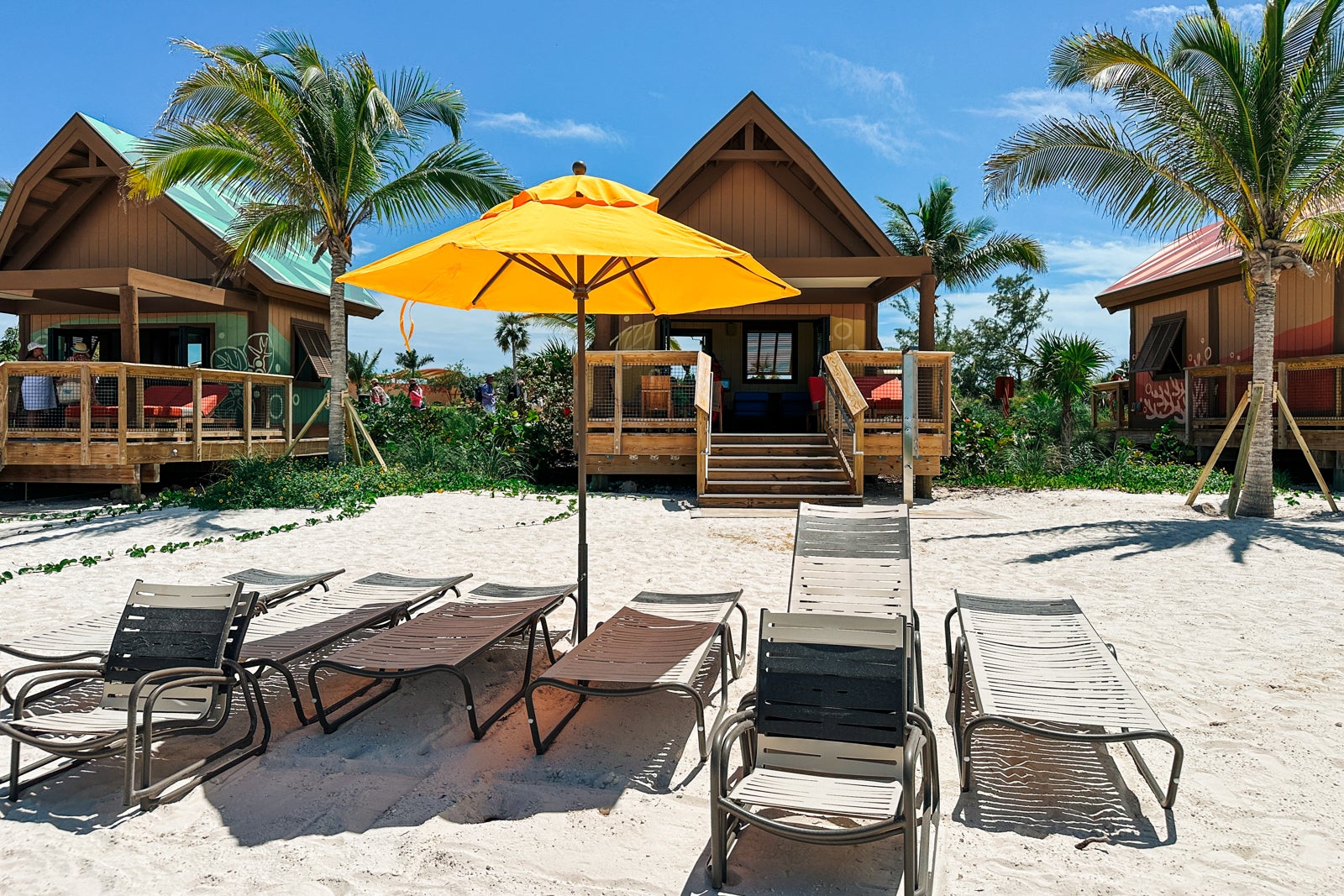 Lounge chairs with an umbrella outside of a private beach cabana